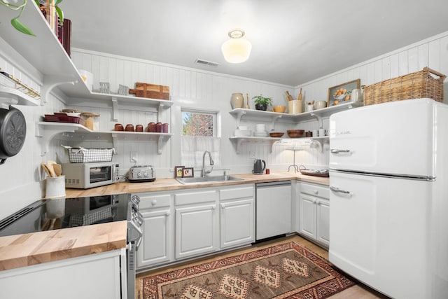 kitchen with butcher block countertops, dishwasher, sink, stainless steel range with electric cooktop, and white fridge