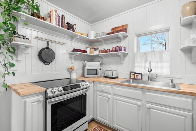 kitchen featuring butcher block counters, sink, white cabinetry, ornamental molding, and stainless steel electric stove