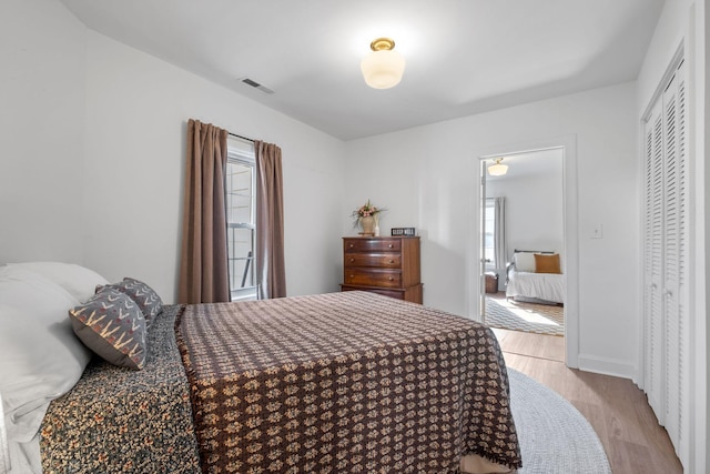 bedroom featuring multiple windows, a closet, and light wood-type flooring