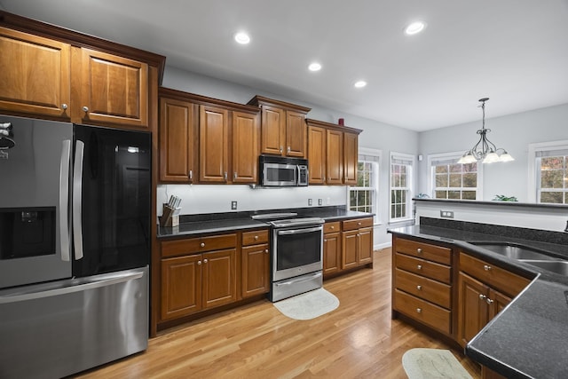 kitchen featuring appliances with stainless steel finishes, sink, light wood-type flooring, and plenty of natural light