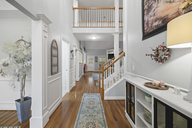 foyer featuring dark hardwood / wood-style flooring, a towering ceiling, and decorative columns