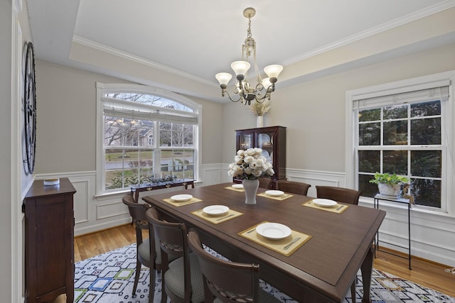 dining area with an inviting chandelier, ornamental molding, and light hardwood / wood-style flooring