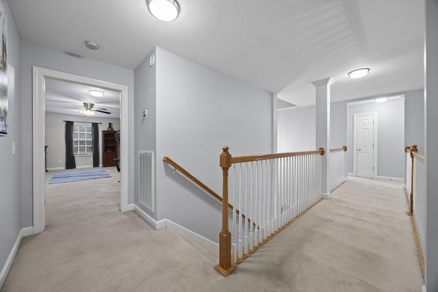 hallway featuring decorative columns and light carpet