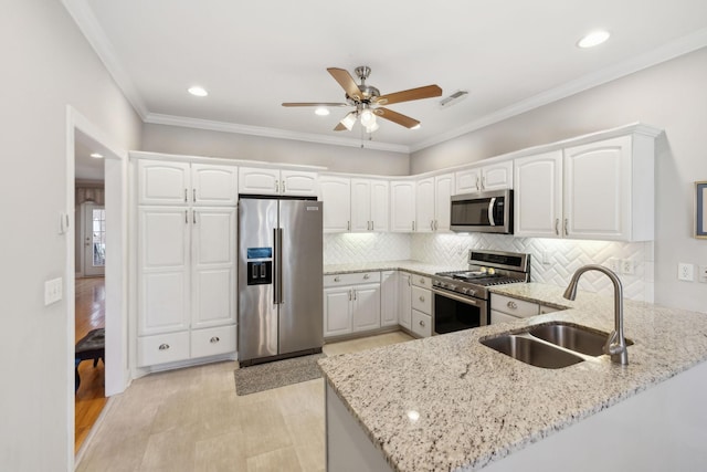 kitchen with sink, white cabinets, kitchen peninsula, stainless steel appliances, and light stone countertops