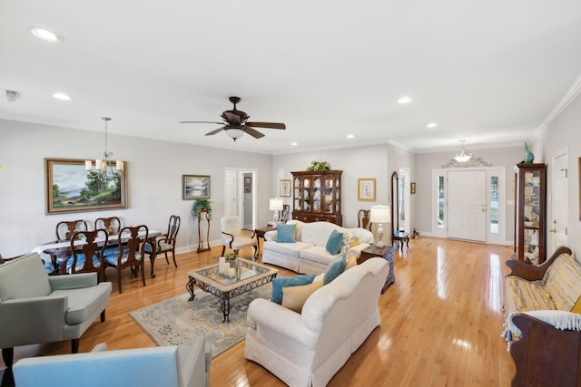 living room with crown molding, light hardwood / wood-style flooring, and ceiling fan with notable chandelier