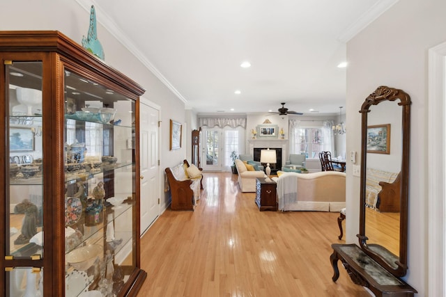 living room with ornamental molding, ceiling fan, and light wood-type flooring