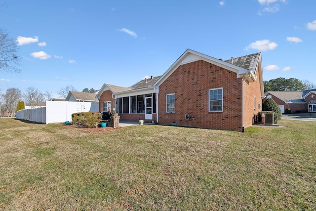 back of property with cooling unit, a yard, and a sunroom