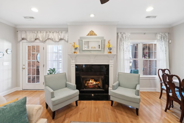 living area with ornamental molding and light hardwood / wood-style flooring