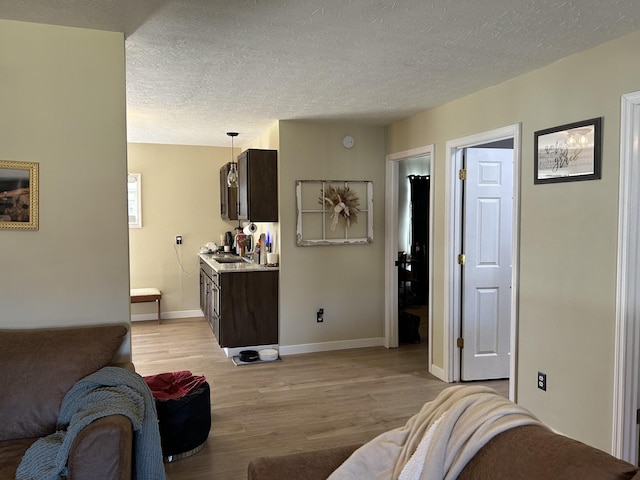 living room with sink, light hardwood / wood-style flooring, and a textured ceiling