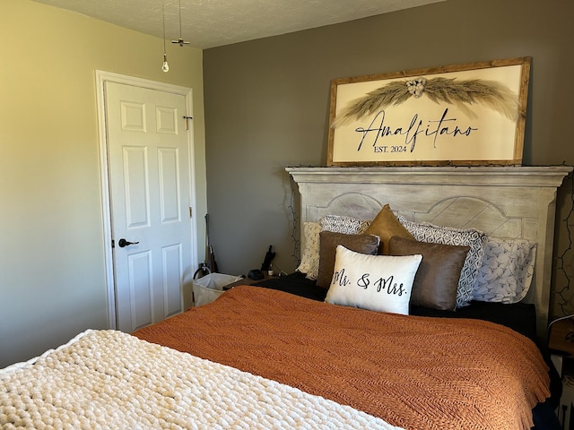 bedroom with a stone fireplace and a textured ceiling