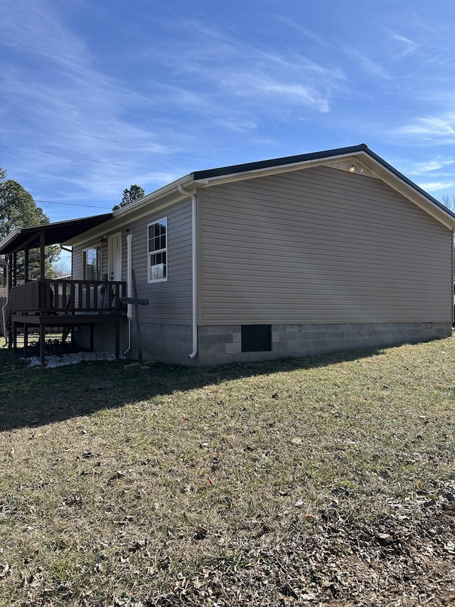 view of side of home with a wooden deck and a yard