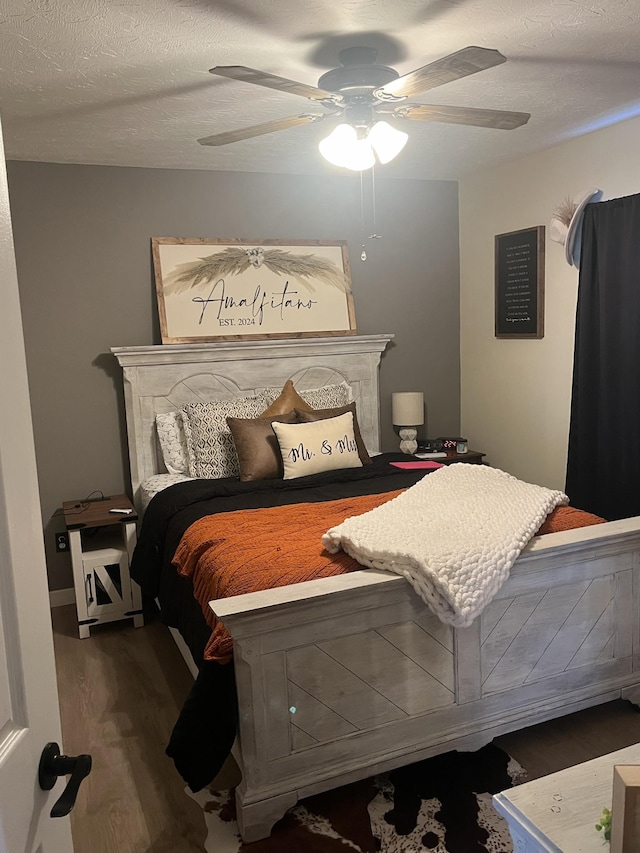 bedroom featuring ceiling fan, wood-type flooring, and a textured ceiling