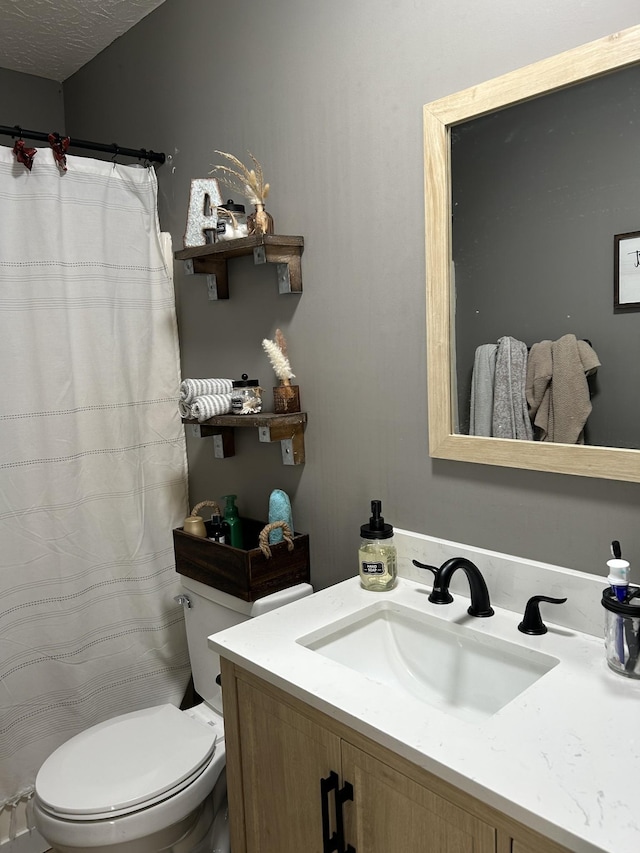 bathroom with vanity, toilet, and a textured ceiling