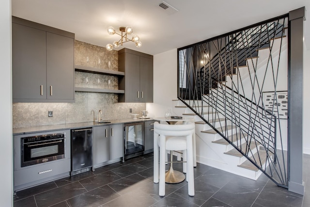 kitchen featuring wall oven, sink, decorative backsplash, and gray cabinetry