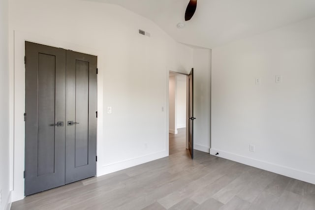 unfurnished bedroom featuring ceiling fan, light hardwood / wood-style floors, vaulted ceiling, and a closet