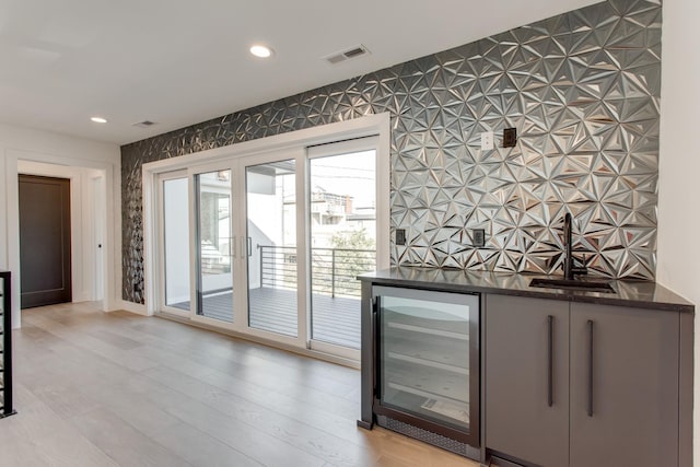 interior space with beverage cooler, sink, and light hardwood / wood-style flooring