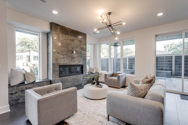 tiled living room with a wealth of natural light, a tile fireplace, and a notable chandelier