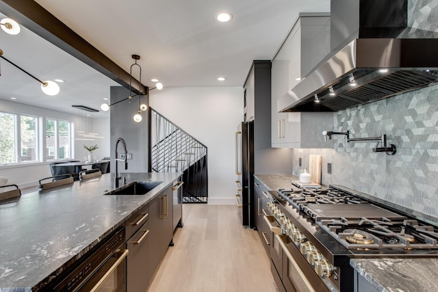 kitchen with ventilation hood, sink, and dark stone countertops