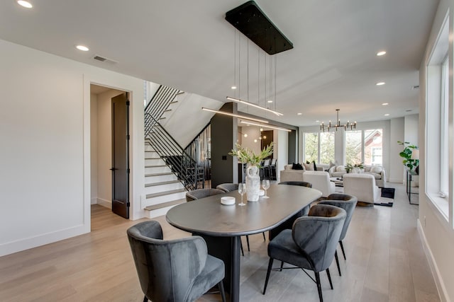 dining space with a notable chandelier and light hardwood / wood-style flooring