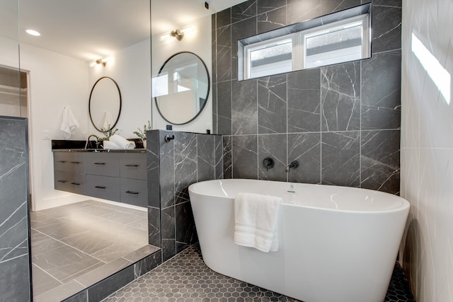 bathroom featuring vanity, tile walls, tile patterned floors, and a tub to relax in