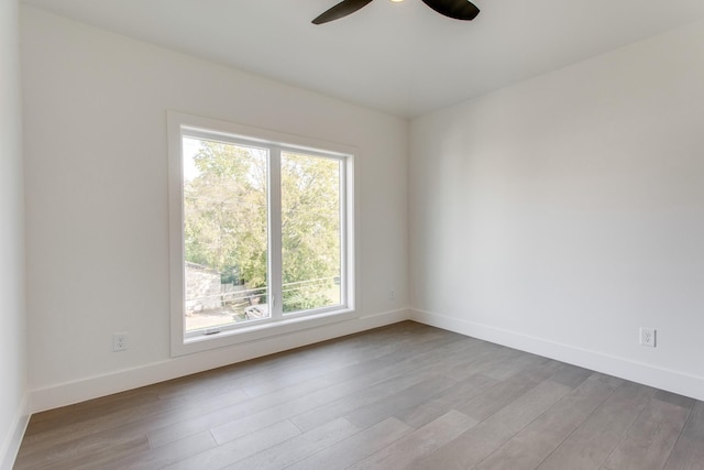 empty room with ceiling fan and light hardwood / wood-style flooring