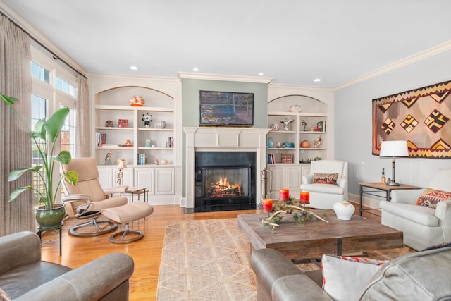 living room with built in shelves, crown molding, and light wood-type flooring