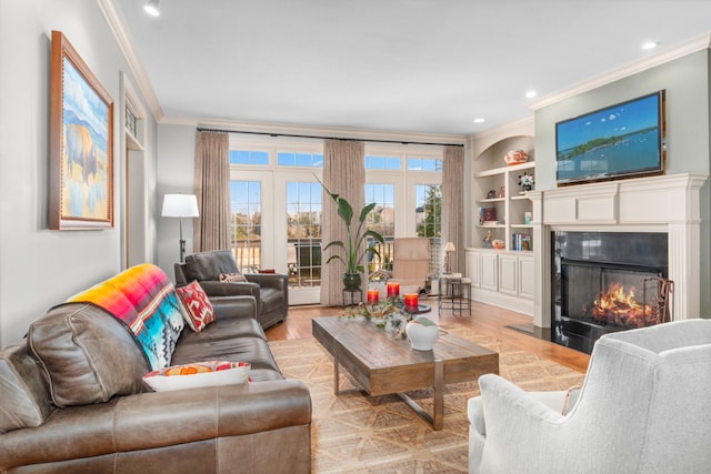 living room with built in shelves, ornamental molding, and light wood-type flooring