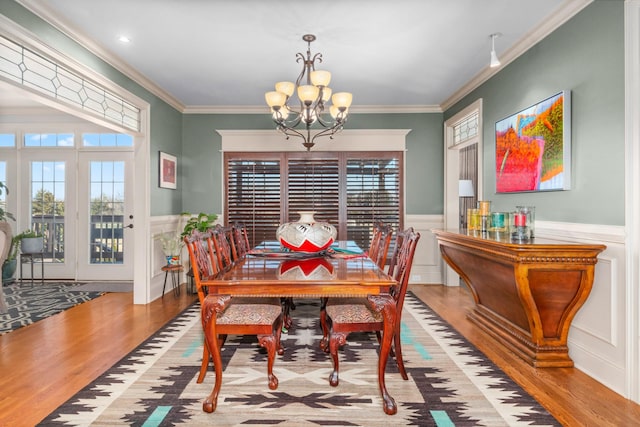 dining space with a notable chandelier, wood-type flooring, and ornamental molding