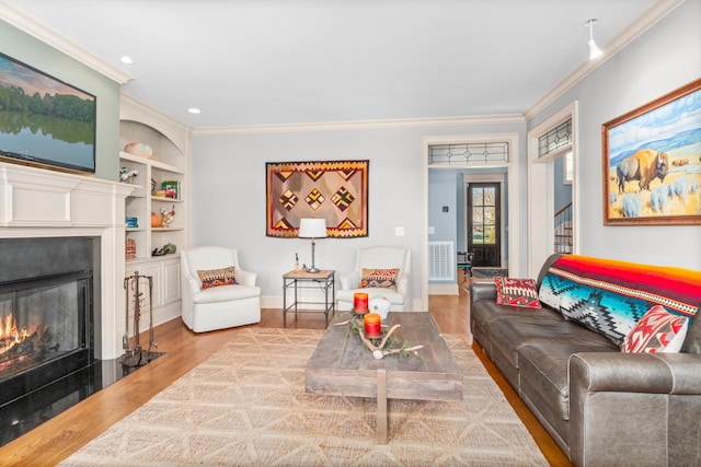 living room featuring built in shelves, wood-type flooring, and ornamental molding