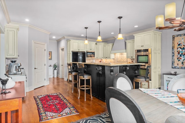 kitchen with pendant lighting, cream cabinets, a kitchen breakfast bar, black fridge, and light stone countertops