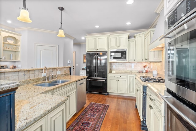 kitchen with sink, decorative light fixtures, appliances with stainless steel finishes, light stone countertops, and cream cabinets