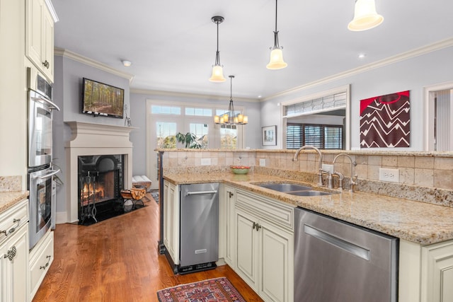 kitchen featuring light stone counters, sink, pendant lighting, and appliances with stainless steel finishes