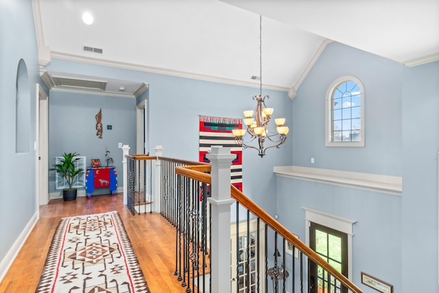 hall with crown molding, lofted ceiling, wood-type flooring, and a chandelier