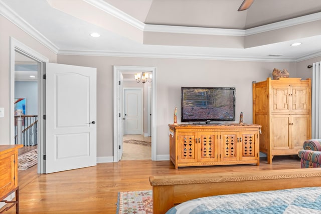 bedroom featuring crown molding, wood-type flooring, and a tray ceiling