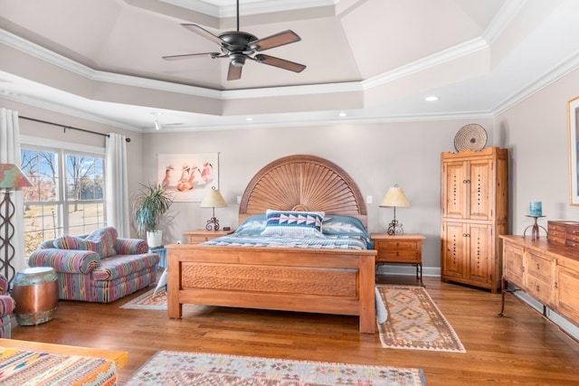 bedroom with a tray ceiling, ornamental molding, ceiling fan, and light wood-type flooring