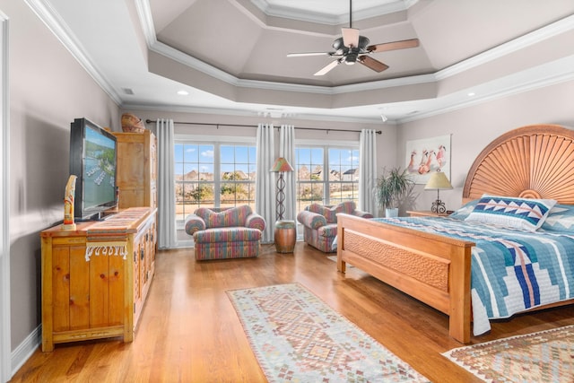 bedroom featuring a raised ceiling, crown molding, ceiling fan, and light hardwood / wood-style flooring