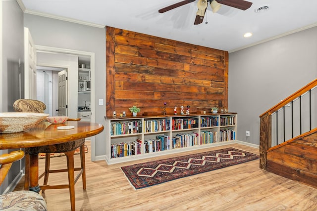 living area featuring crown molding, light hardwood / wood-style floors, and ceiling fan