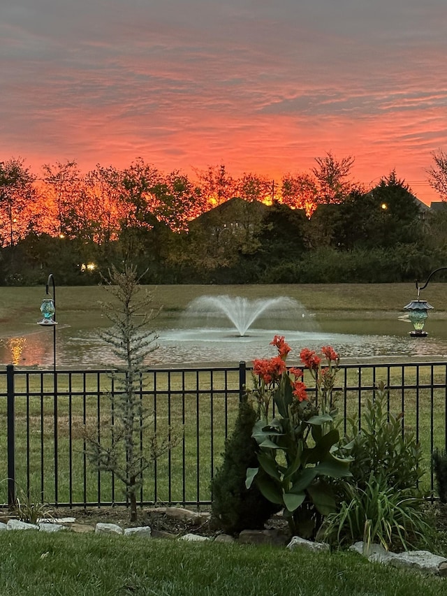 yard at dusk featuring a water view