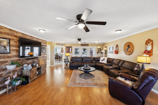 living room with a textured ceiling, wooden walls, ornamental molding, and wood-type flooring