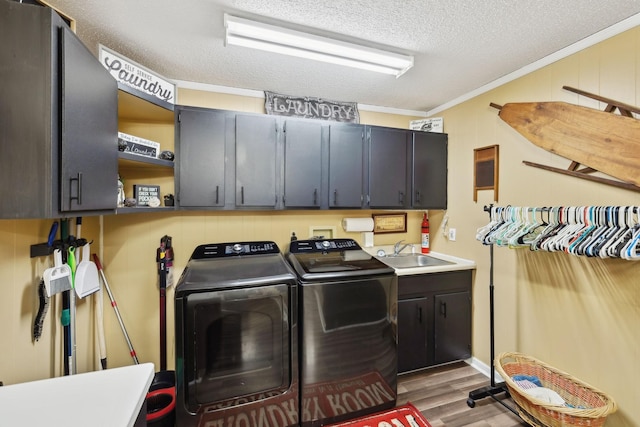 clothes washing area featuring sink, cabinets, separate washer and dryer, a textured ceiling, and ornamental molding