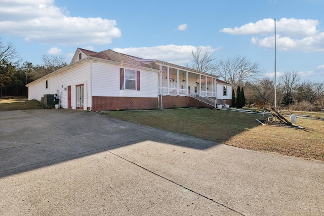 view of front of house with central AC, covered porch, and a front lawn