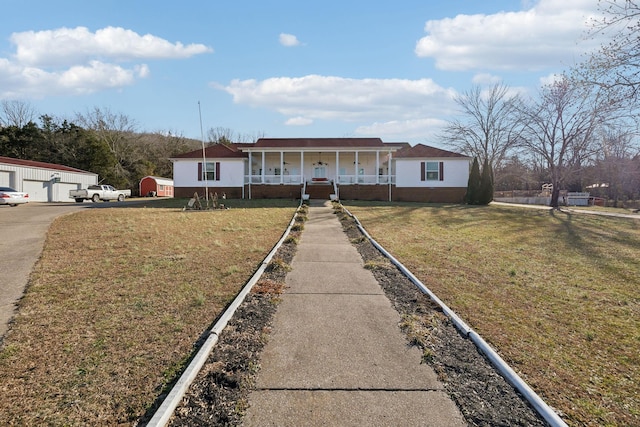 ranch-style house with an outbuilding, a porch, a garage, and a front yard