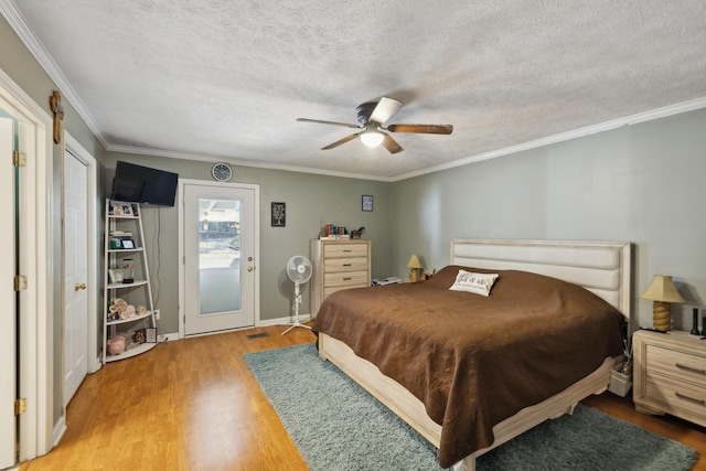 bedroom featuring wood-type flooring, crown molding, a textured ceiling, and ceiling fan