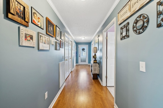 hall featuring crown molding, a textured ceiling, and light wood-type flooring