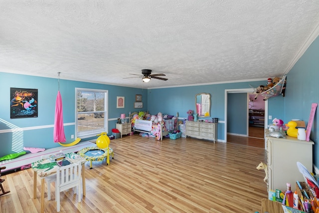 game room with hardwood / wood-style flooring, ceiling fan, crown molding, and a textured ceiling