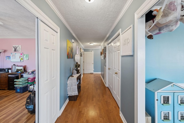 corridor with hardwood / wood-style flooring, ornamental molding, and a textured ceiling