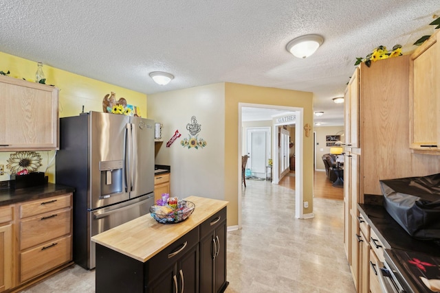 kitchen with wood counters, stainless steel fridge with ice dispenser, a center island, and a textured ceiling