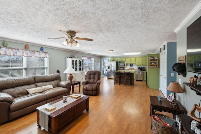 living room featuring ornamental molding, ceiling fan, and light hardwood / wood-style flooring