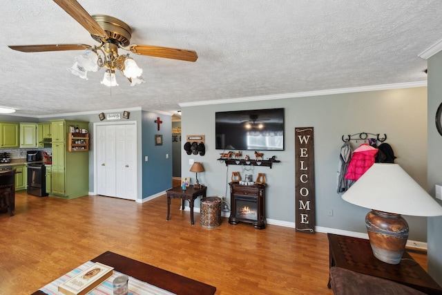 living room featuring a textured ceiling, wood-type flooring, ornamental molding, and ceiling fan