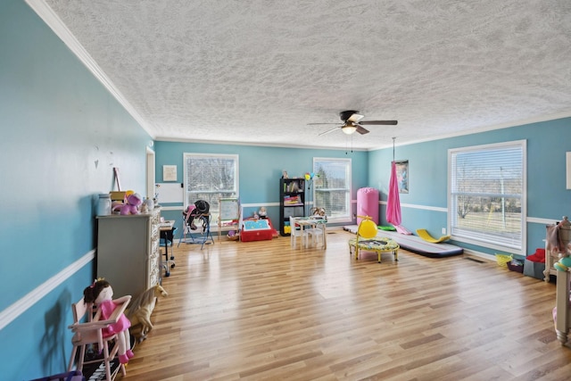 game room with ceiling fan, crown molding, light hardwood / wood-style floors, and a textured ceiling